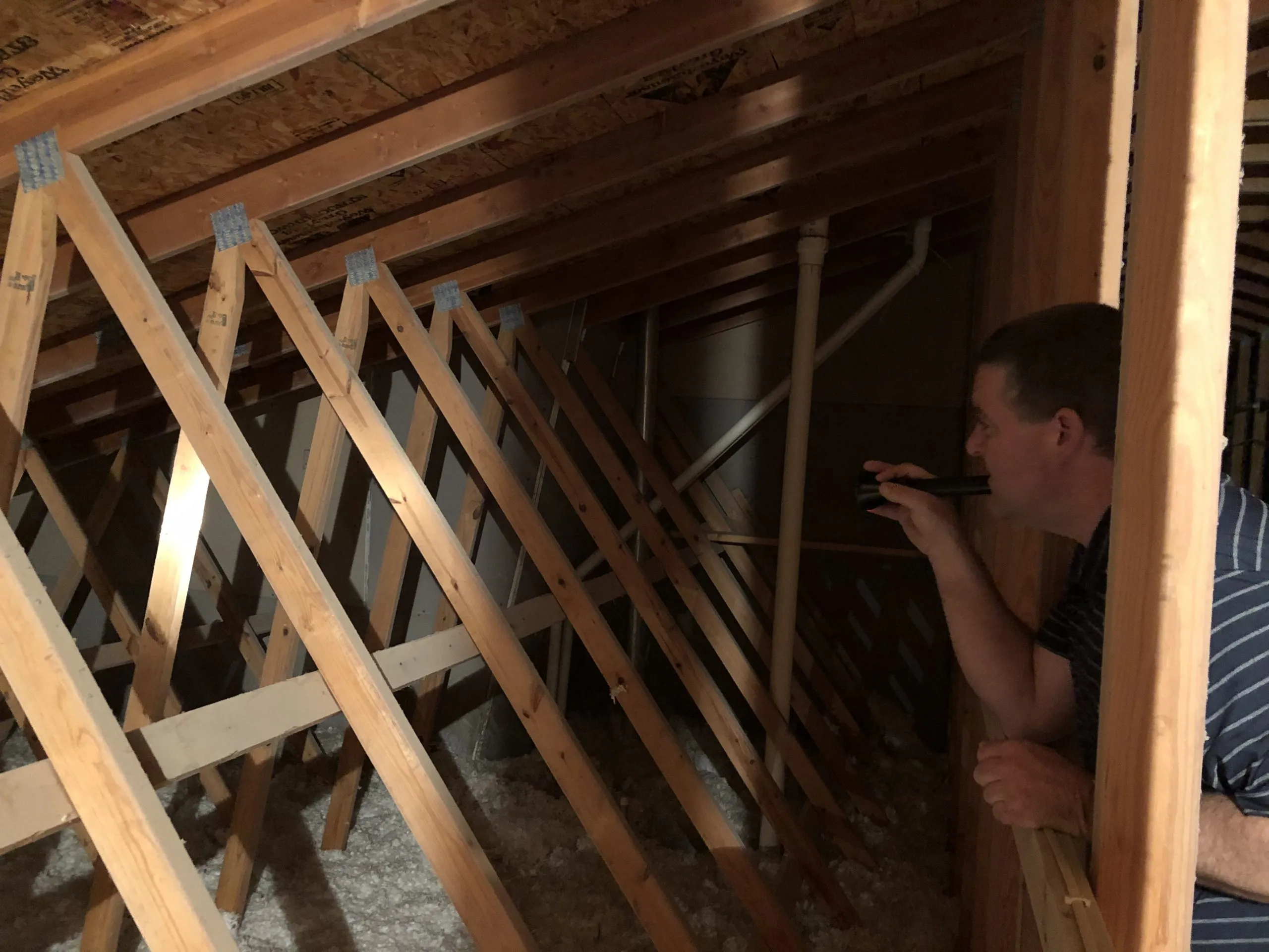 Perry checking roof trusses and ductwork in an attic
